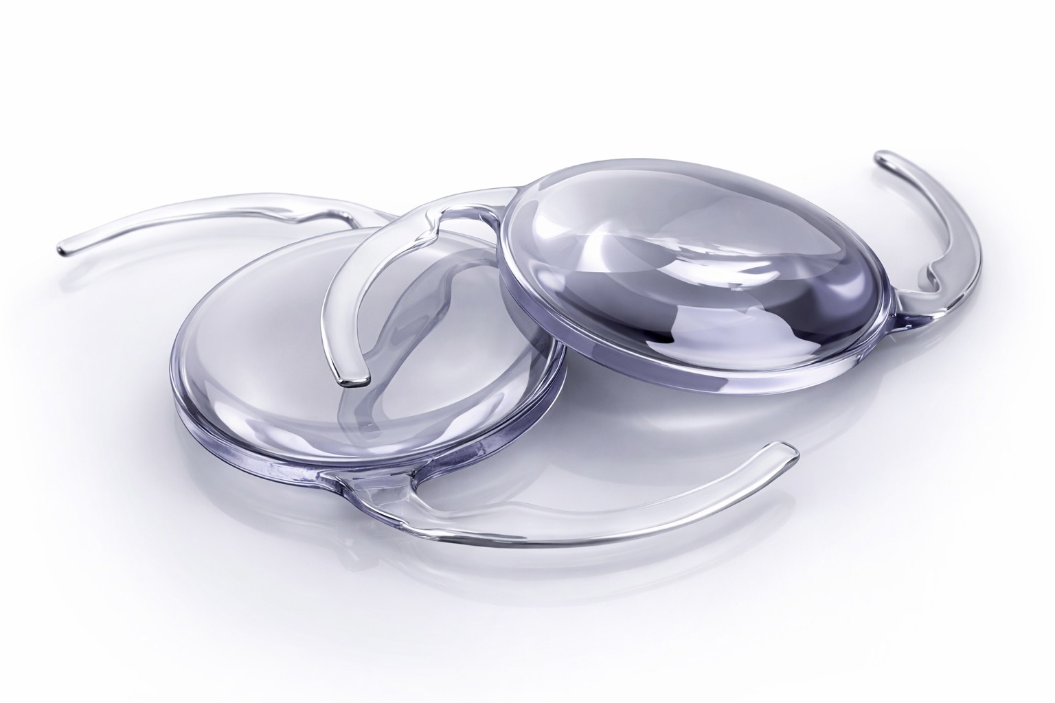 Zwei klare, runde Intraokularlinsen mit gekrümmter Haptik liegen auf einer reflektierenden weißen Oberfläche und sind für die Implantation im Auge während der Katarakt-Chirurgie zur Wiederherstellung der Sehkraft vorgesehen.